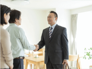 Business professional shaking hands with a couple in a home setting, symbolizing trust and relationship-building