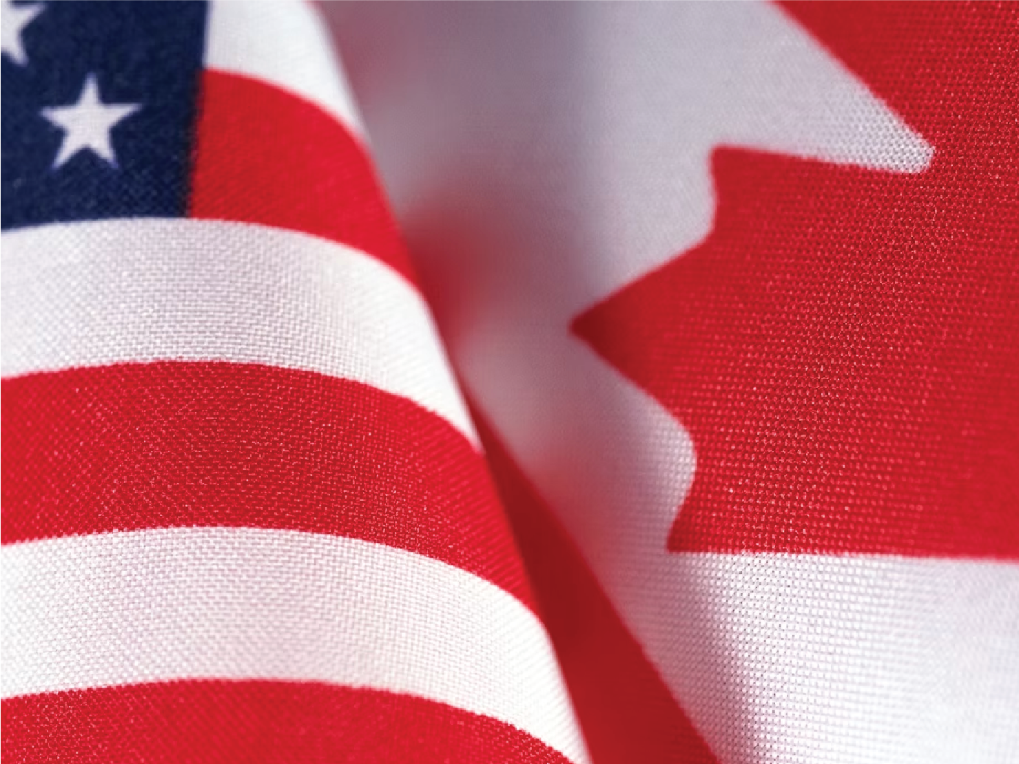 Close-up of overlapping United States and Canadian flags symbolizing international trade relations