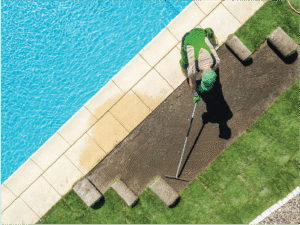 Overhead view of a landscaper laying sod beside a pool and garden edge